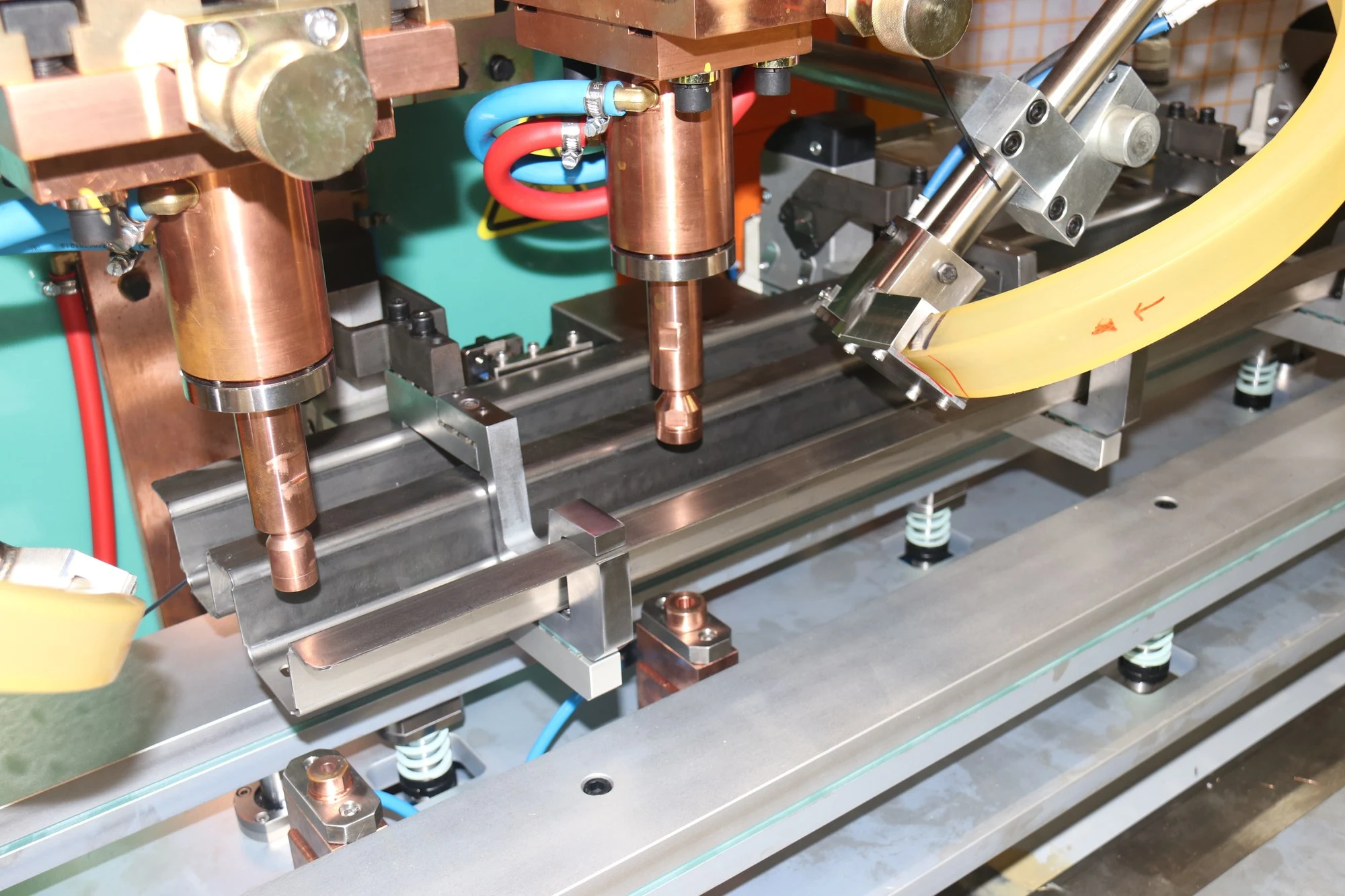 Multi-head MFDC welding station. Two water-cooled electrodes descend onto a formed steel profile held in a fixture.