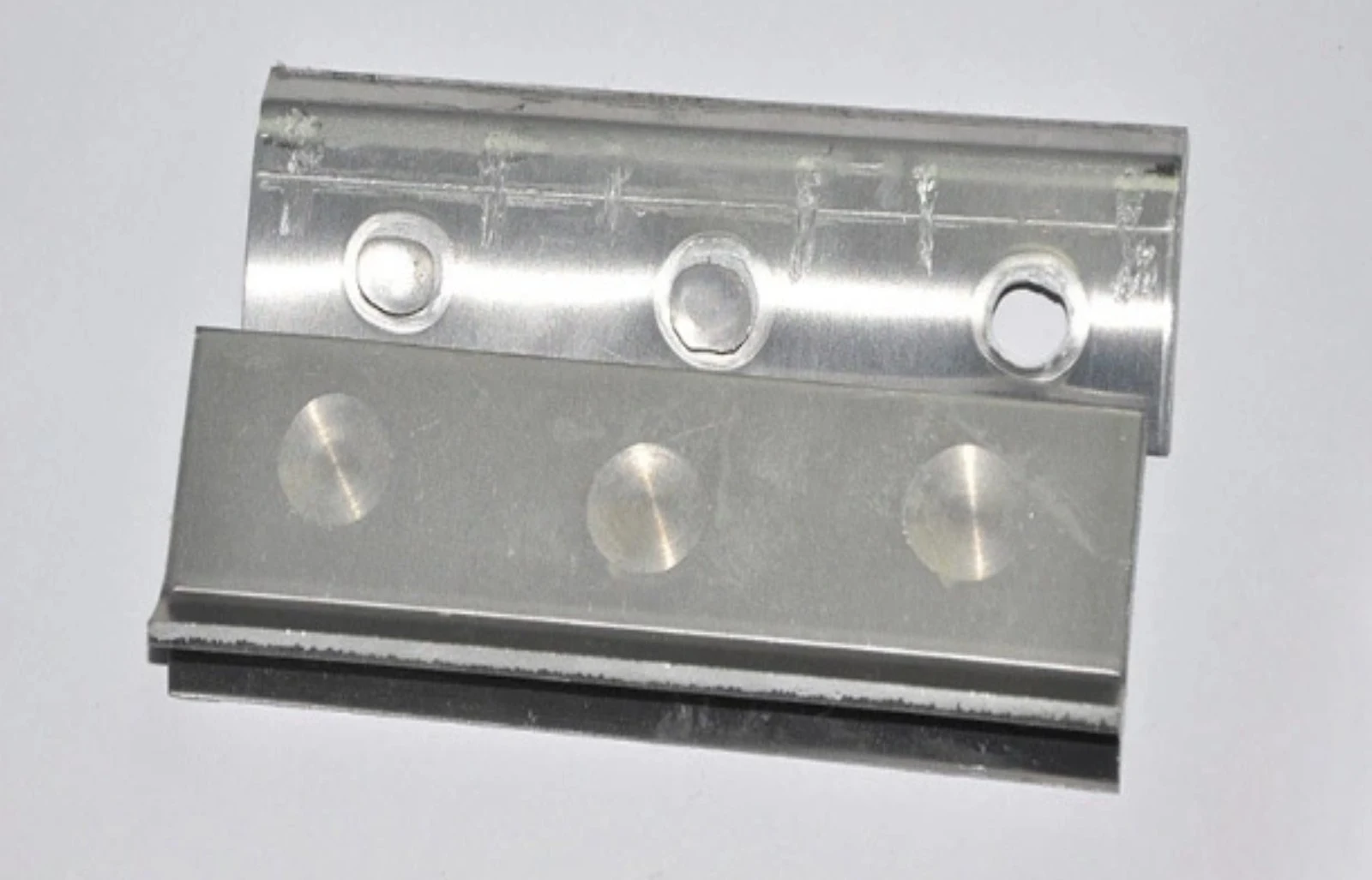 Two bright metal profiles joined with three welds.